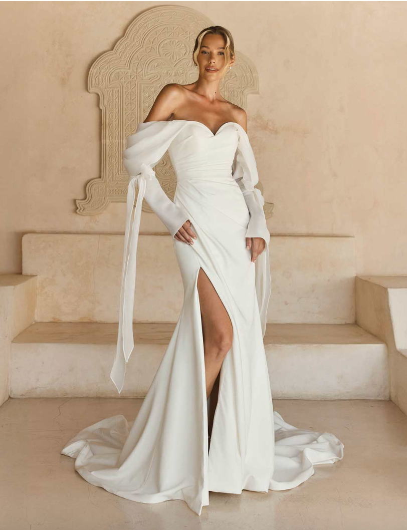 Laiya van Madi Lane heeft een A-lijn silhouet met een laag glitter tule om een ​​extra glans toe te voegen aan haar all-over pailletten kantpatroon. Haar lijfje is ontworpen met een moderne, trendy piek-stijl halslijn met een sexy maar ingetogen illusie plunge. 