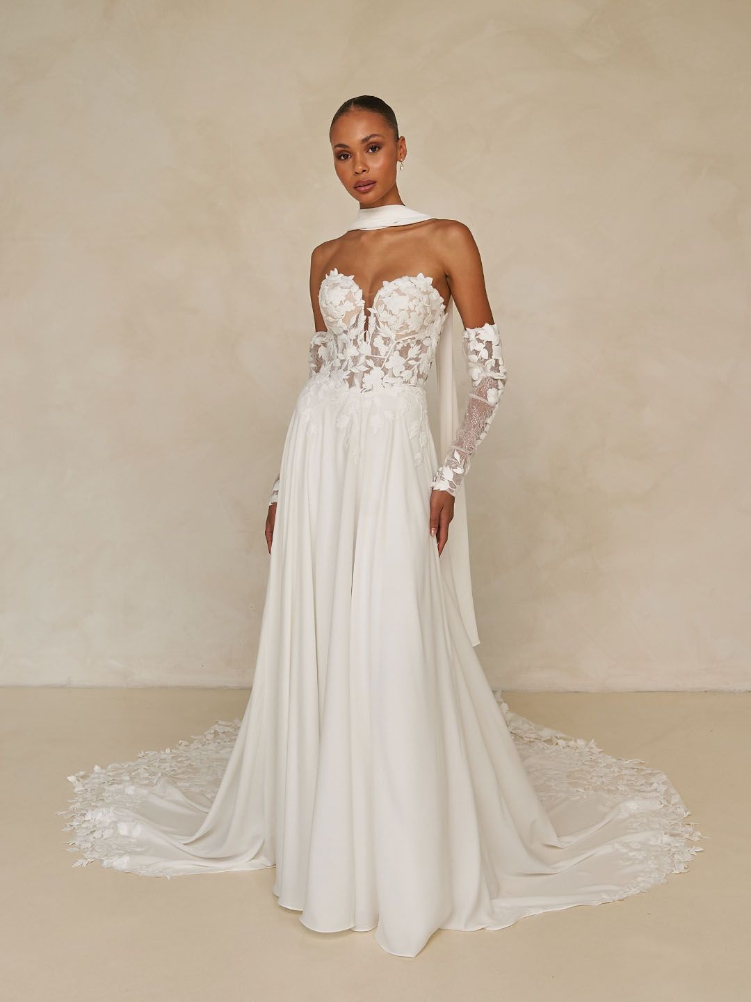 Laiya van Madi Lane heeft een A-lijn silhouet met een laag glitter tule om een ​​extra glans toe te voegen aan haar all-over pailletten kantpatroon. Haar lijfje is ontworpen met een moderne, trendy piek-stijl halslijn met een sexy maar ingetogen illusie plunge. 