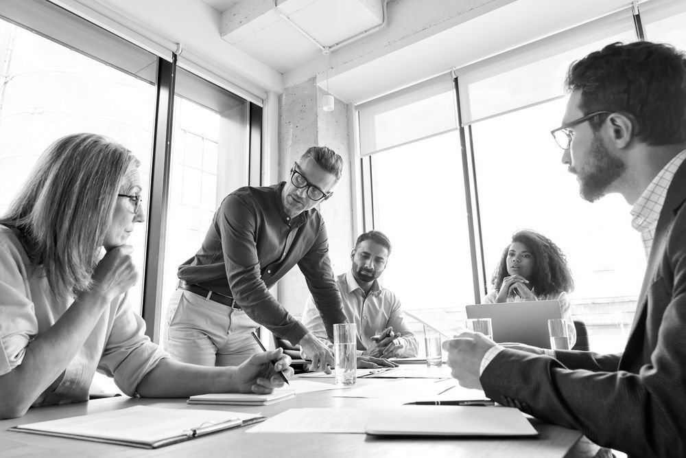 a group of people are sitting around a table having a meeting