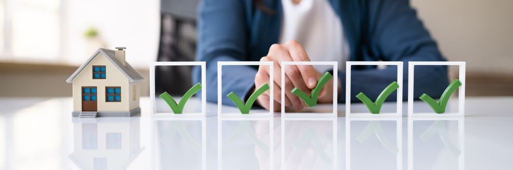 a woman is sitting at a table with a checklist and a model house