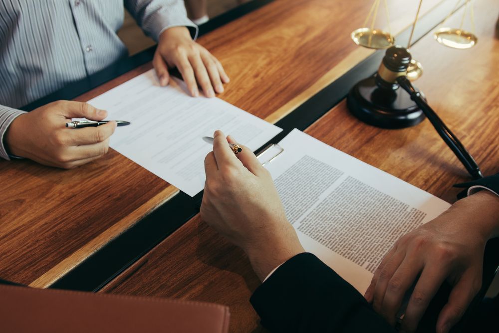 a man and a woman are sitting at a table signing a document