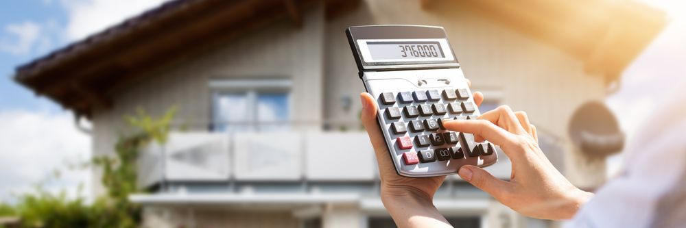 a person is holding a calculator in front of a house