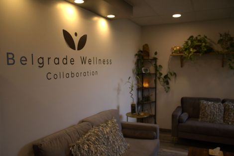 Belgrade Wellness Collaboration waiting area with sofas, plants, and logo on wall.