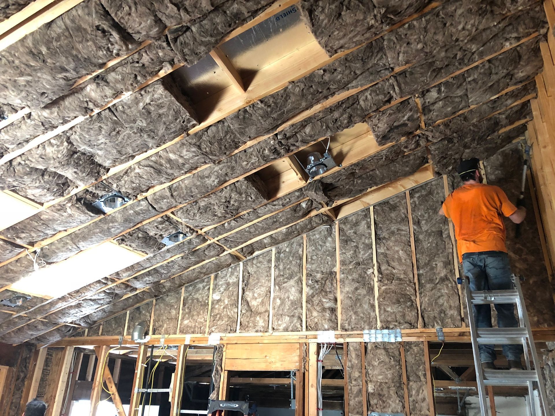 A man is standing on a ladder in an attic.