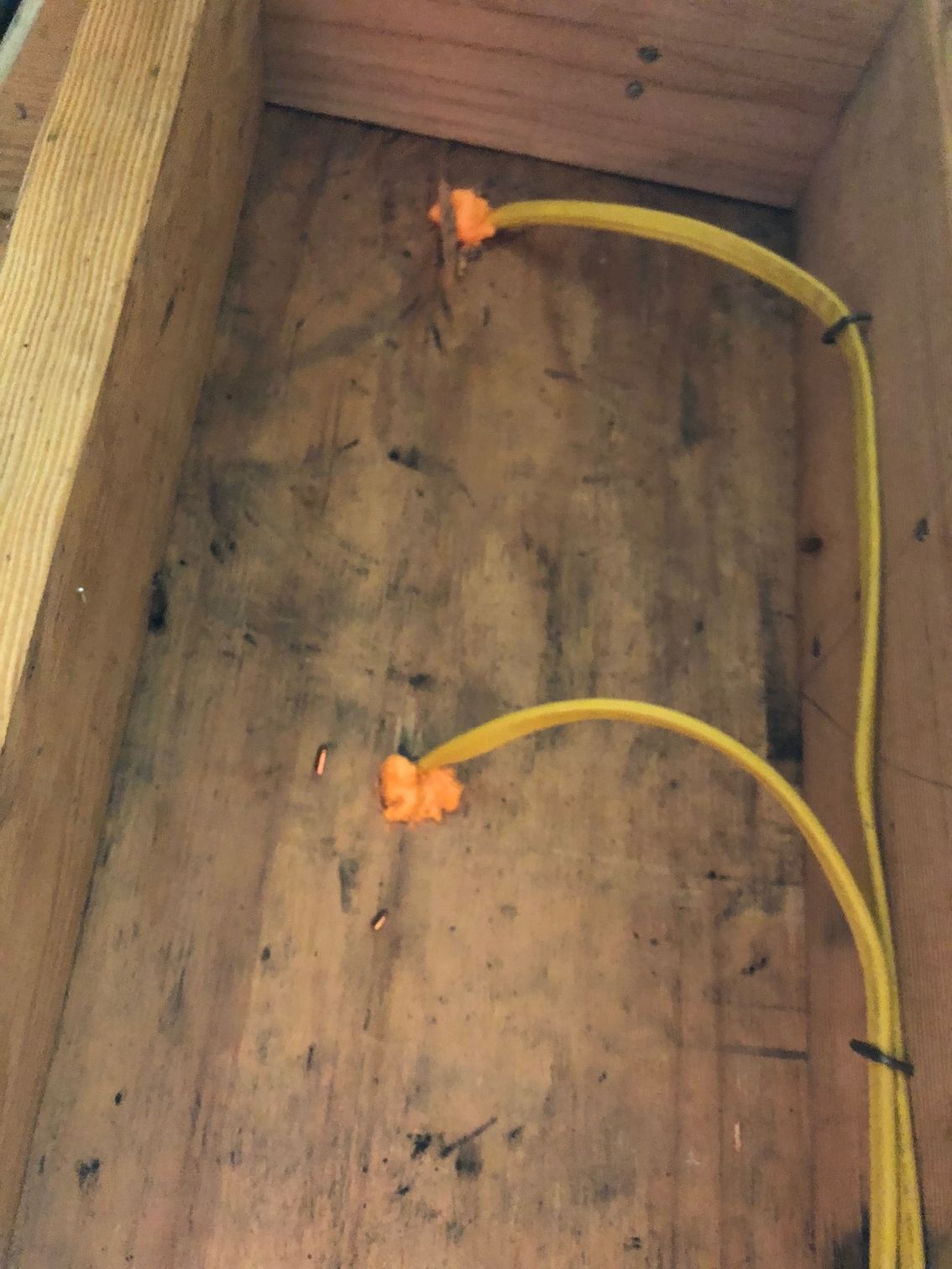 Two yellow wires are connected to each other in a wooden space.