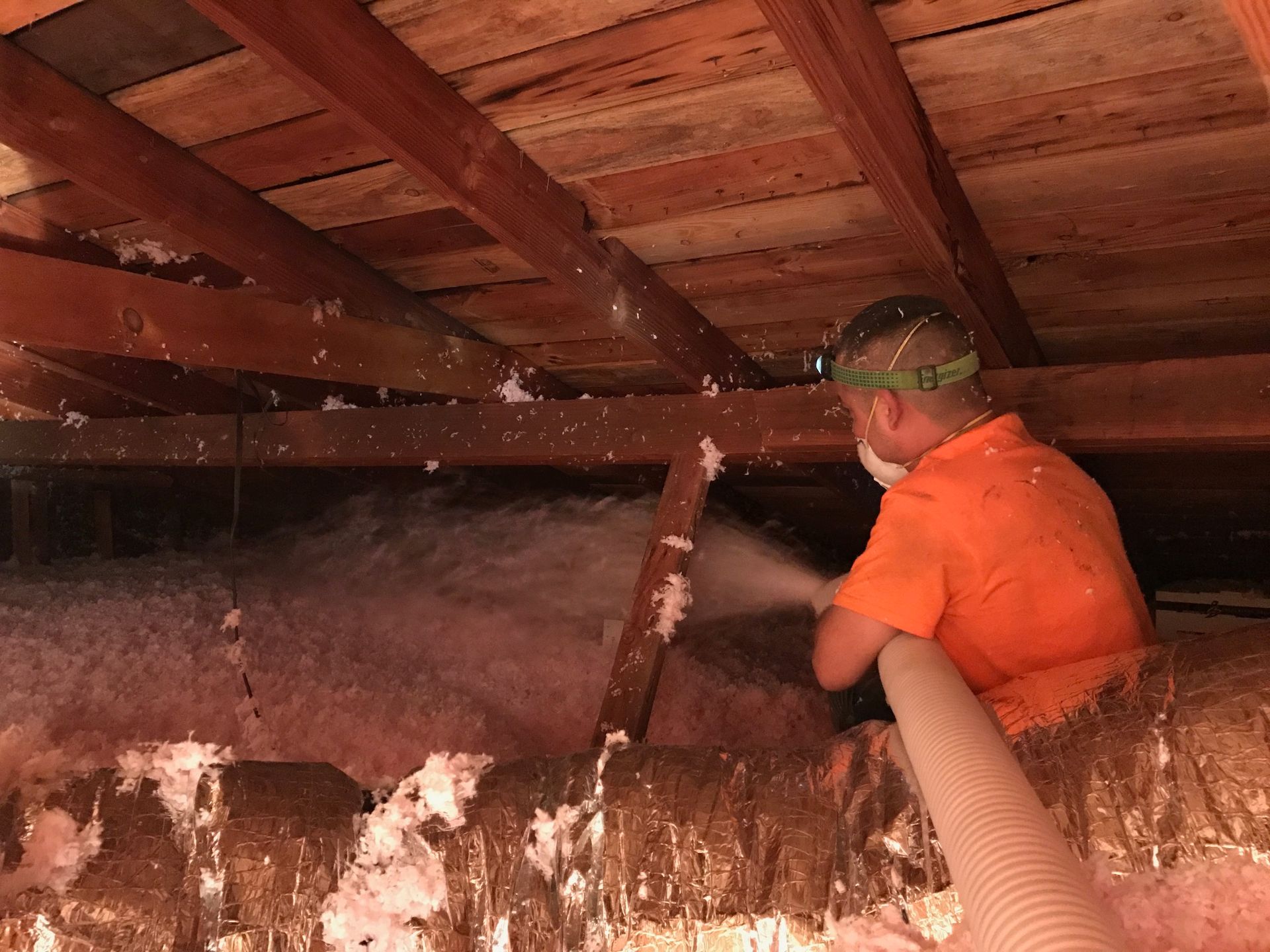 a man is blowing insulation into an attic with a hose .