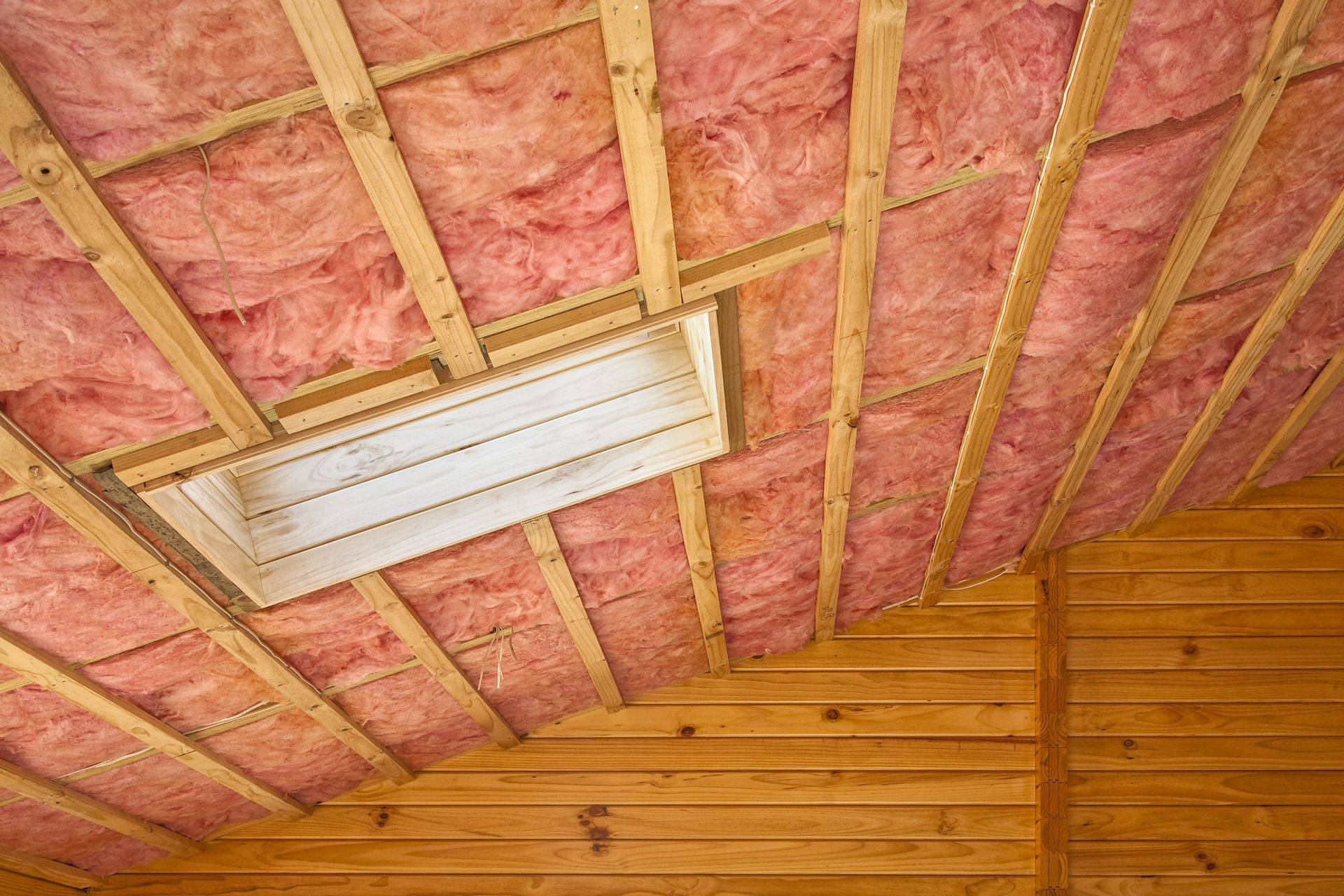 A ceiling with pink insulation and a light on it.