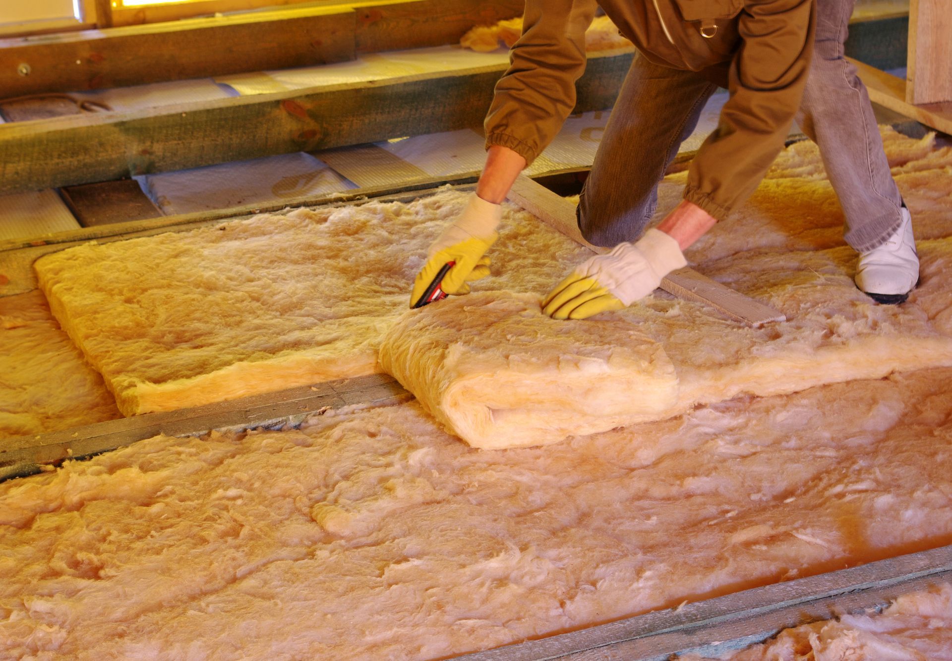 A man is cutting a piece of insulation on the floor.