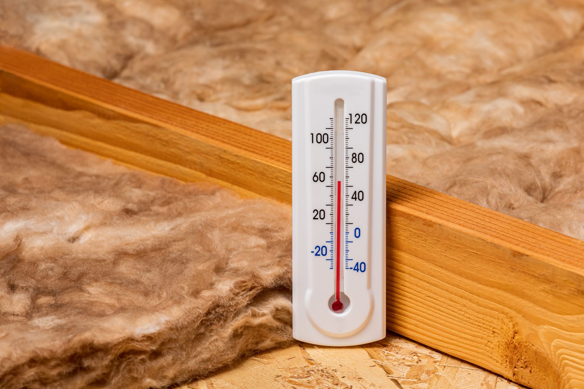 A thermometer is sitting next to a piece of wood.