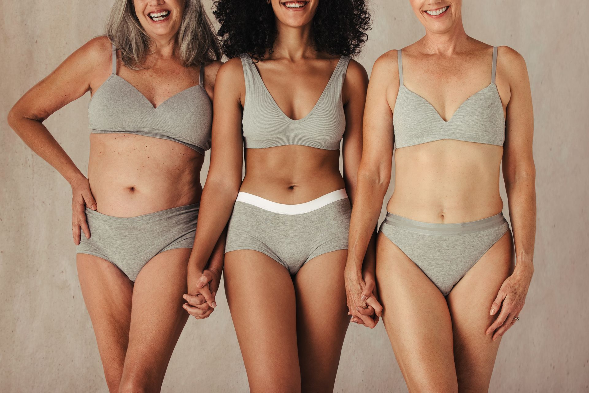 Three women in underwear are holding hands and posing for a picture.