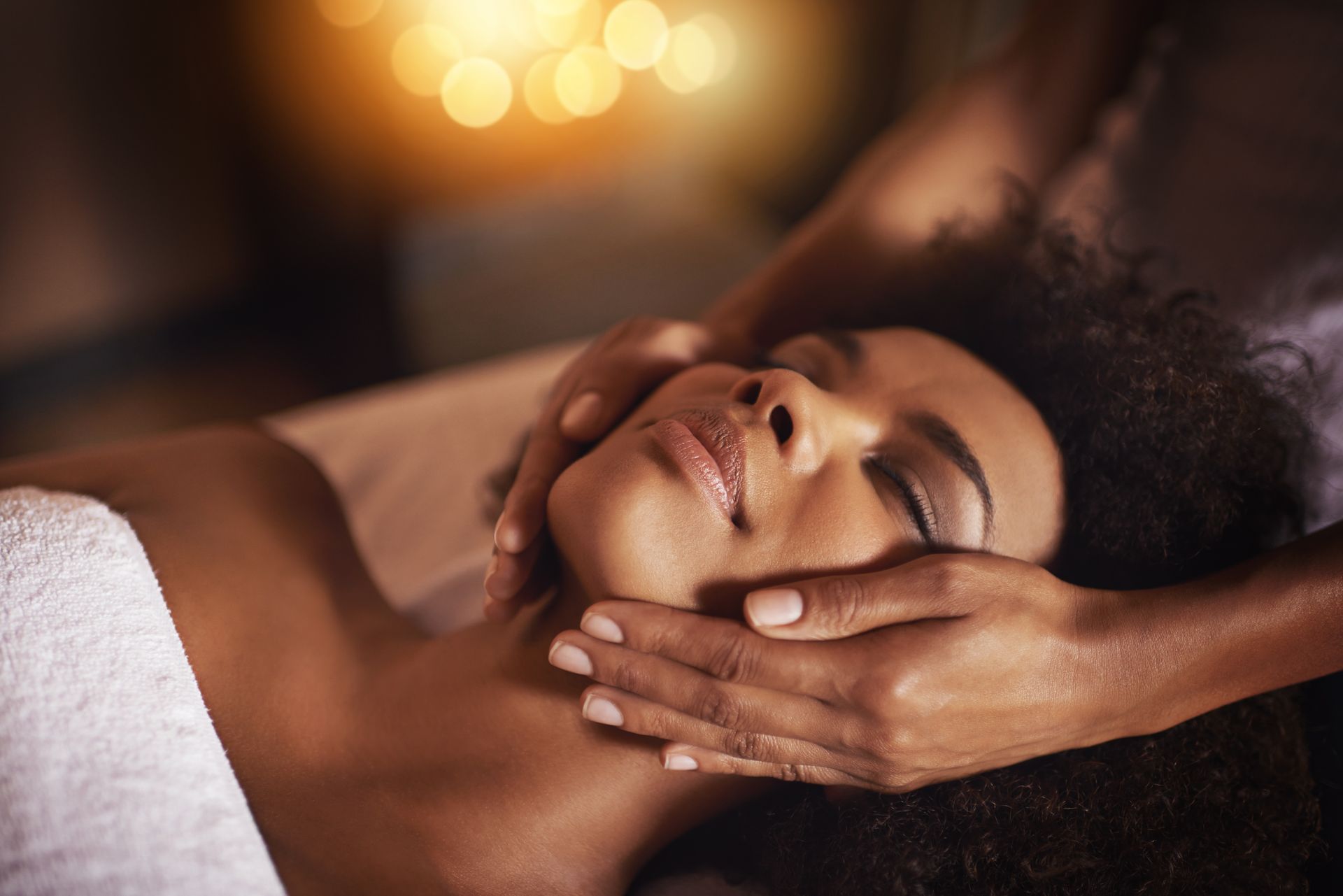 A woman is getting a facial massage at a spa.