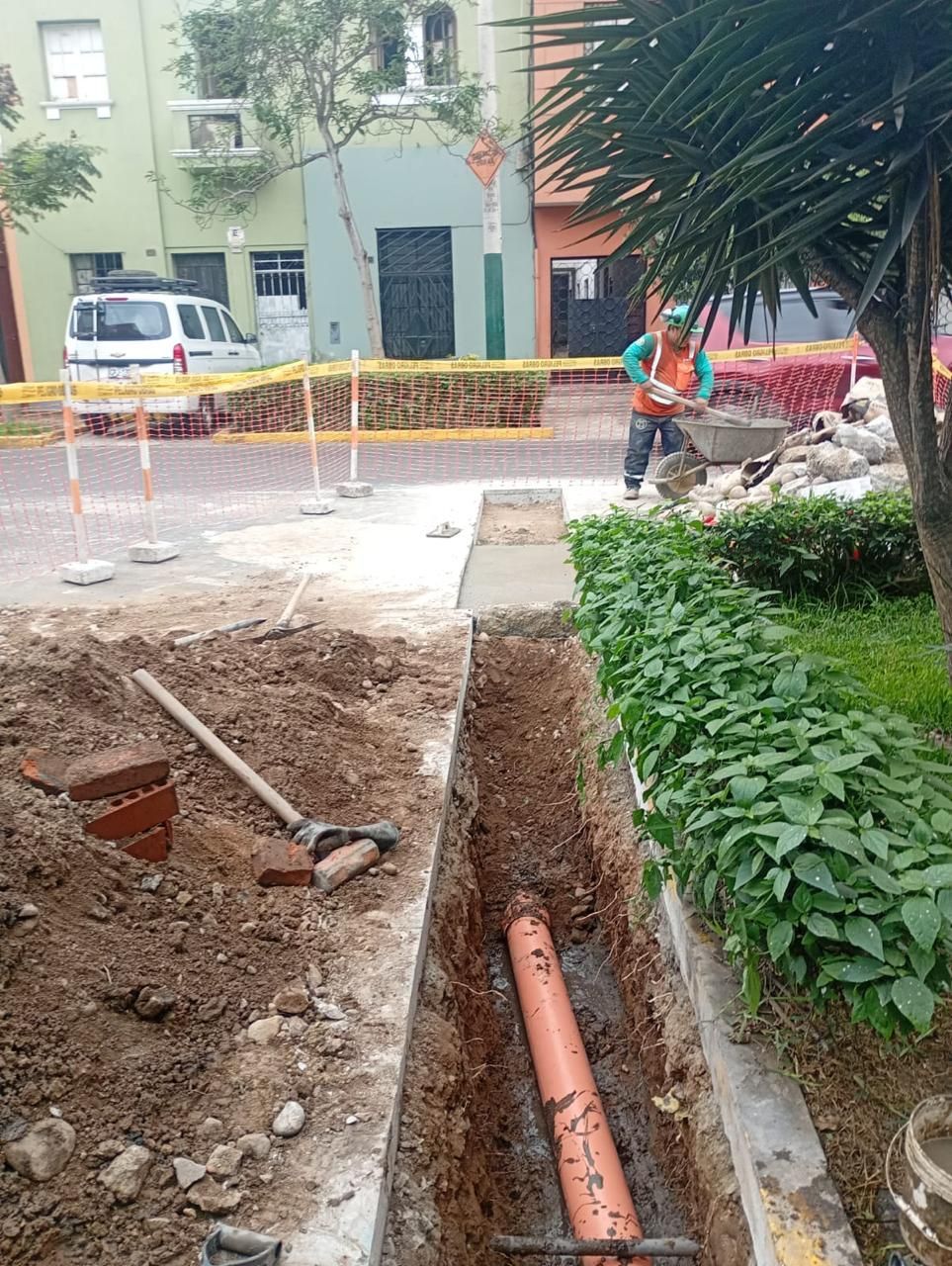 Un trabajador de la construcción con chaleco naranja palea tierra
