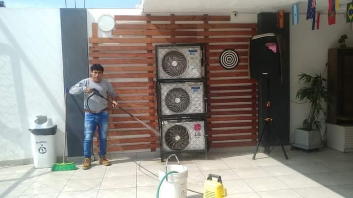 El hombre rocía las unidades de aire acondicionado con agua en el exterior.