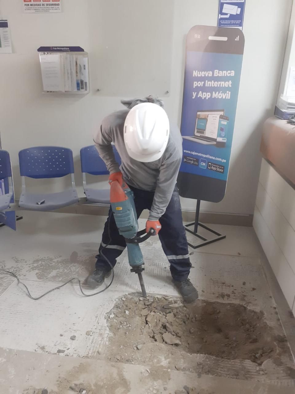 Obrero de la construcción usando un martillo neumático en un interior