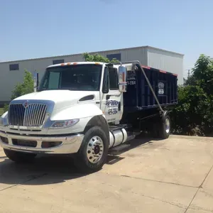 A dump truck is parked in a driveway in front of a building.