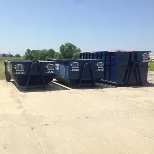 A row of dumpsters are lined up in a parking lot.