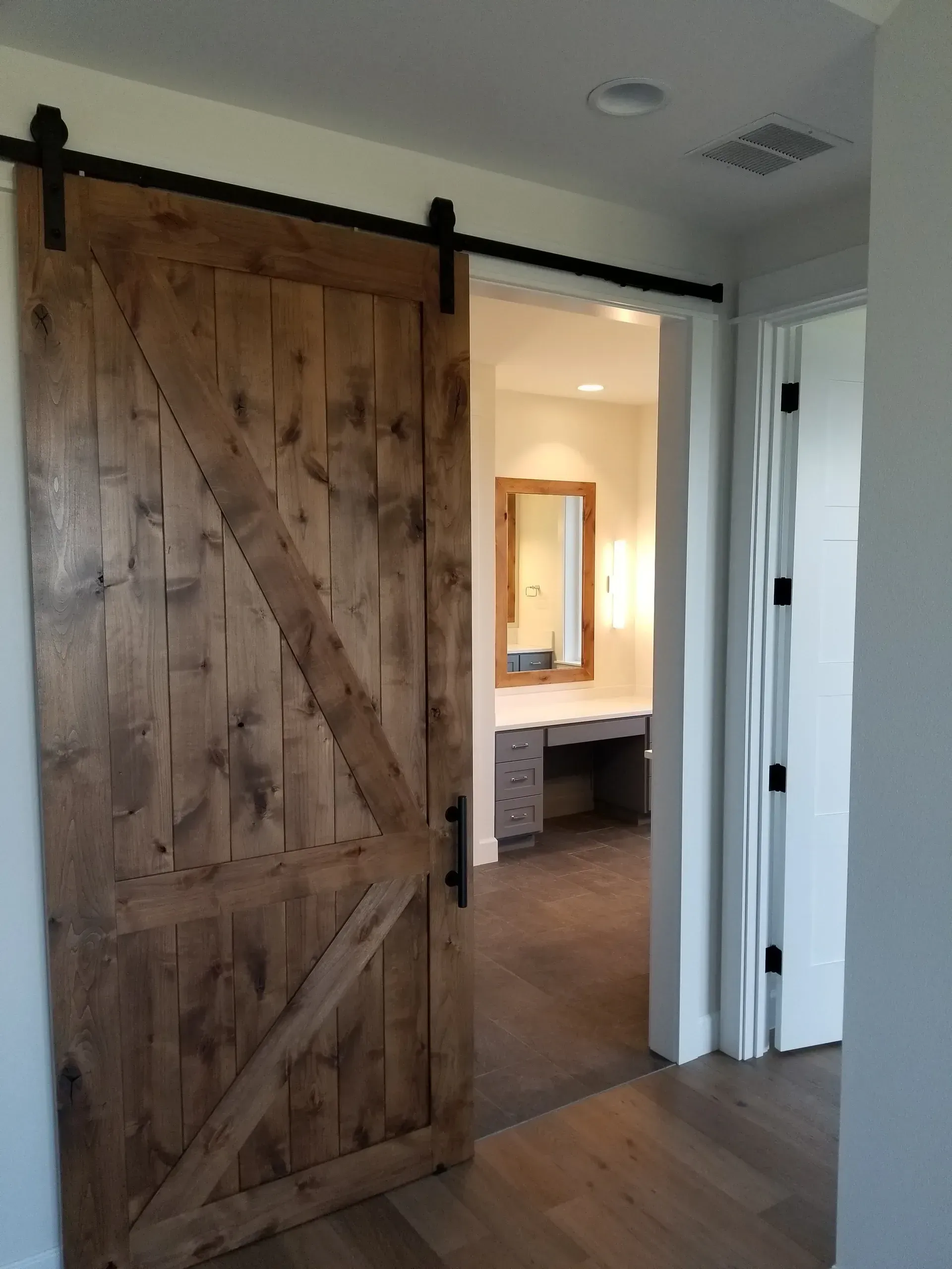 A wooden sliding barn door is open to a bathroom
