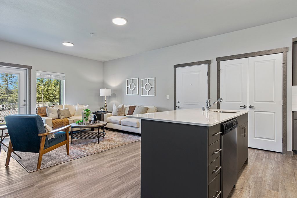 Photo showing a living room area with plenty of open space and a kitchen counter island with a sink