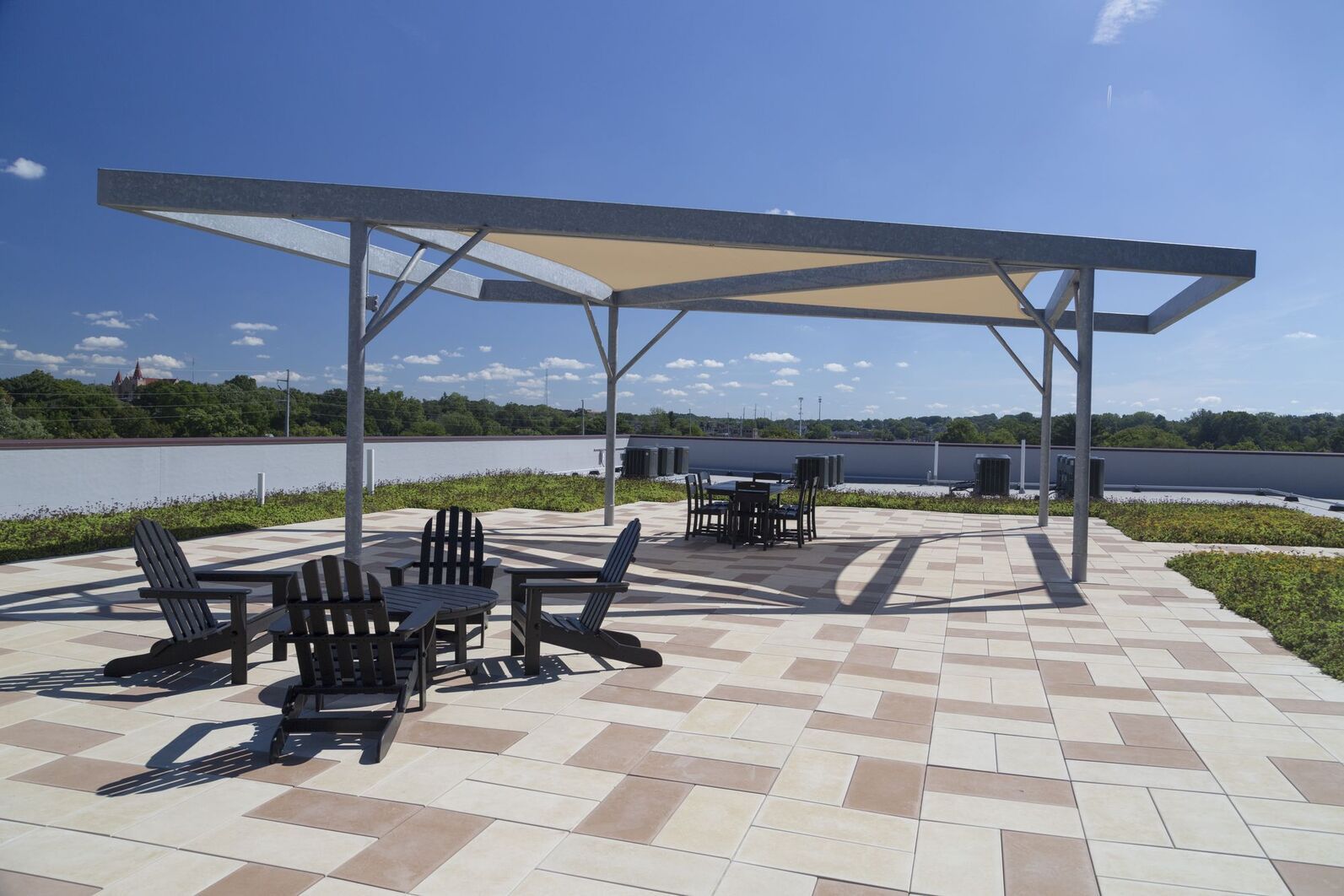 Shaded patio with tables and chairs beside a lake under a clear blue sky