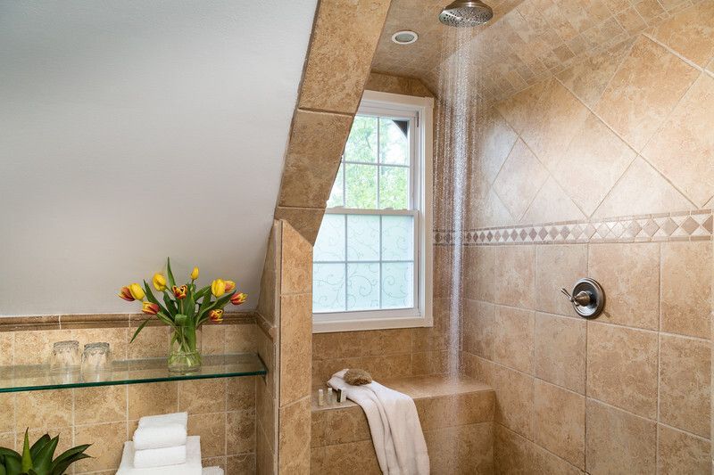 A bathroom with a walk in shower and a window.