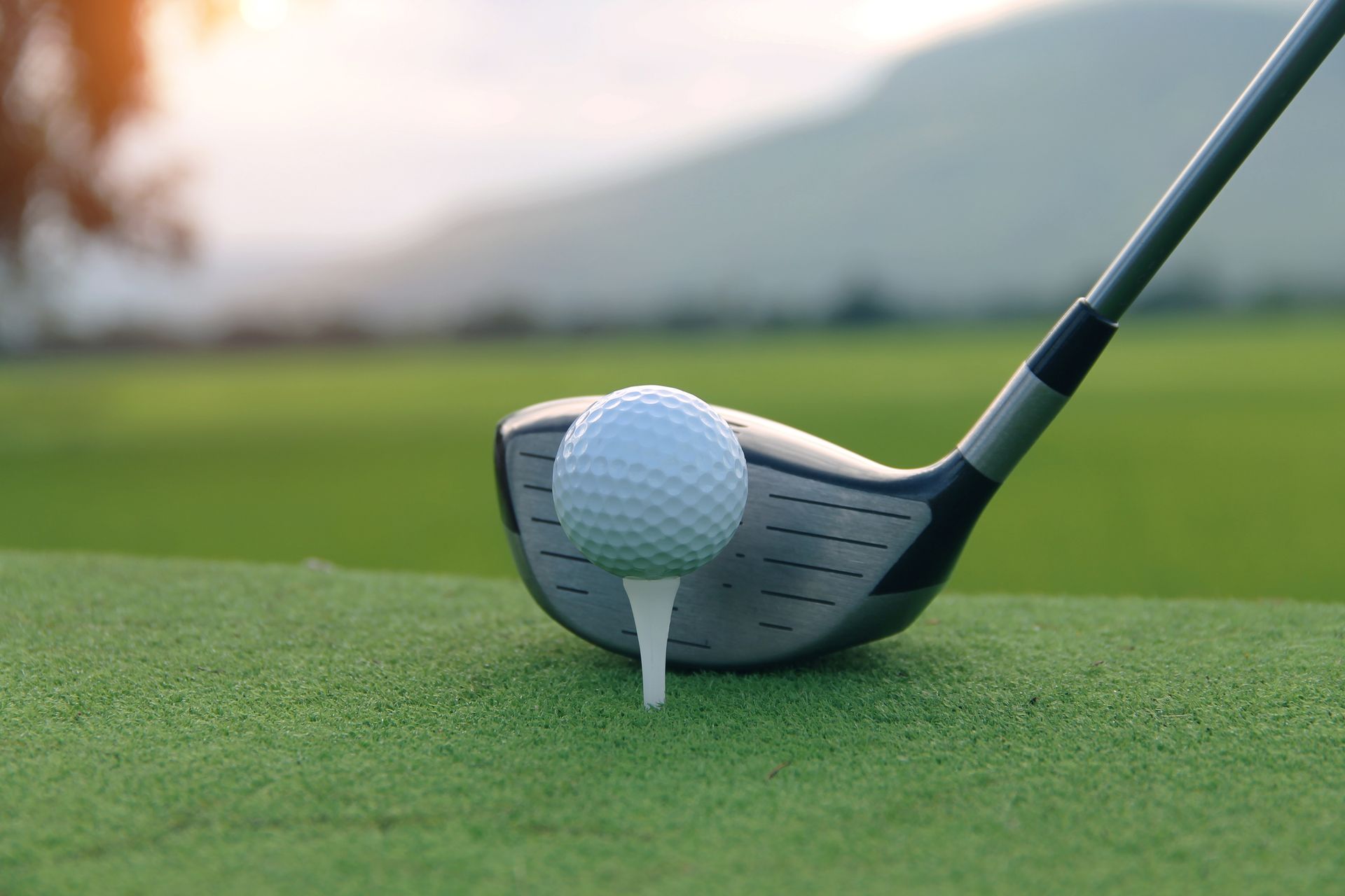 A close up of a golf ball on a tee with a golf club.