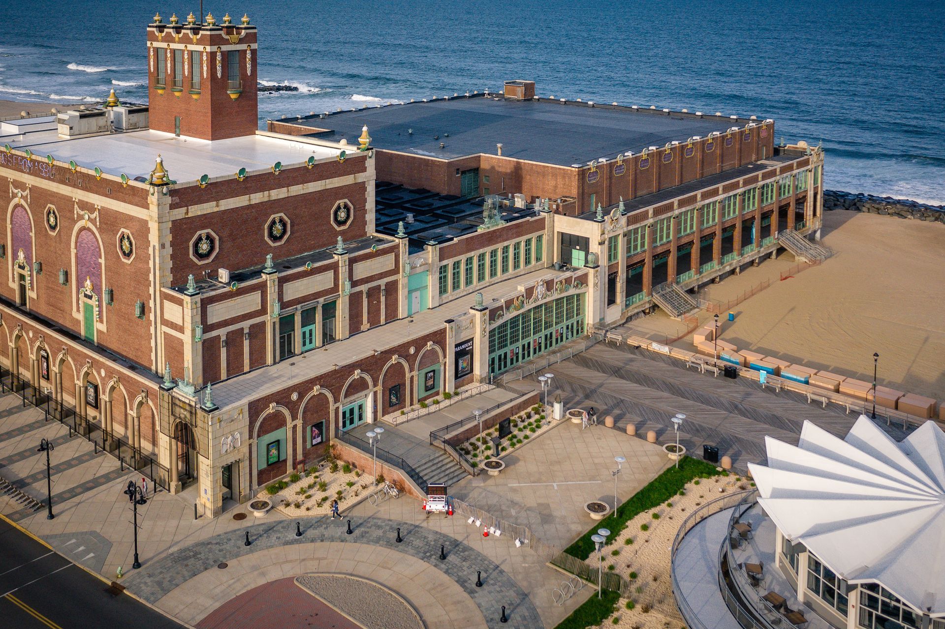 An aerial view of a large brick building next to the ocean.