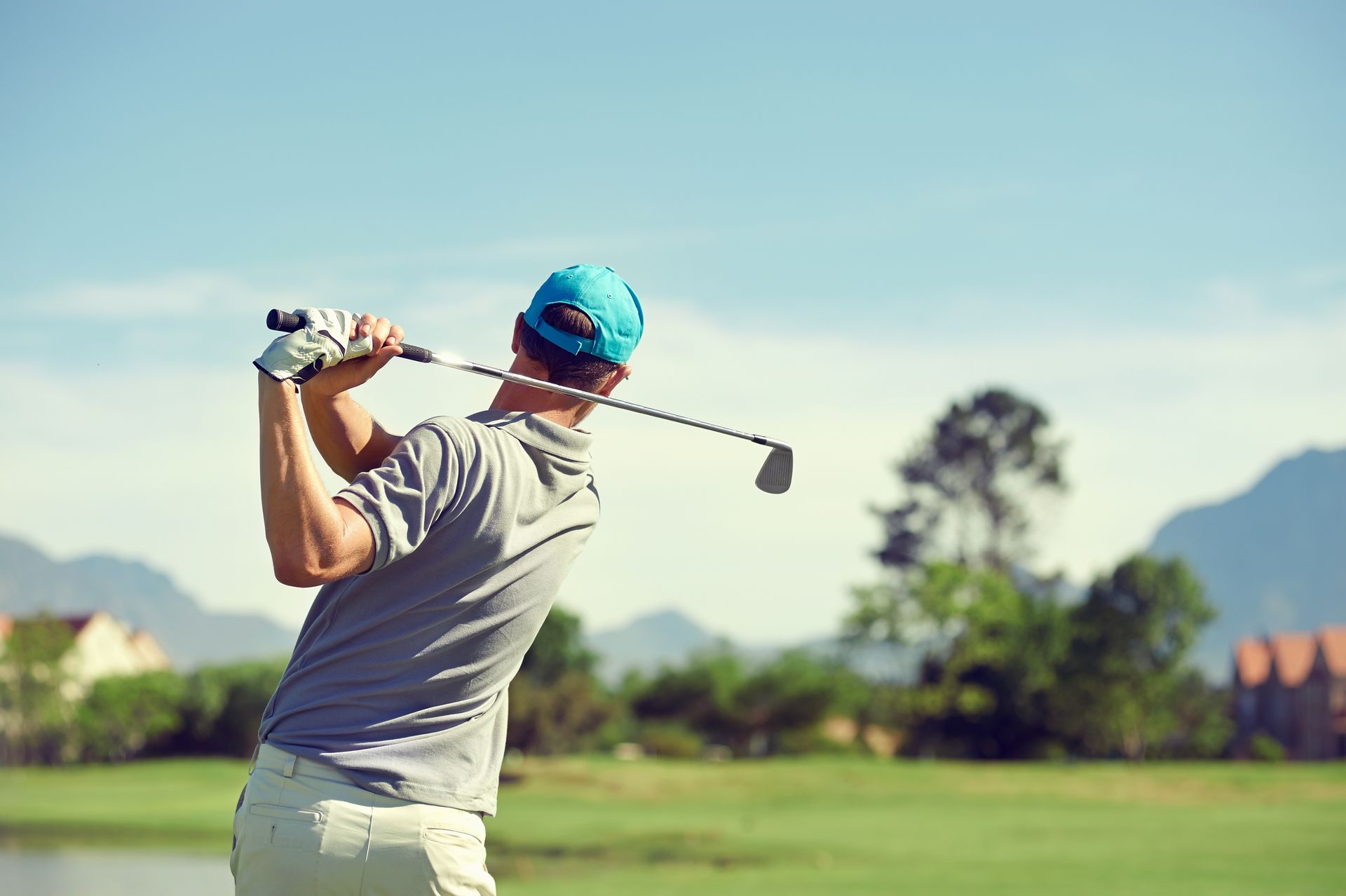 A man is swinging a golf club on a golf course.