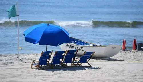 A blue umbrella is sitting on a beach next to a boat.