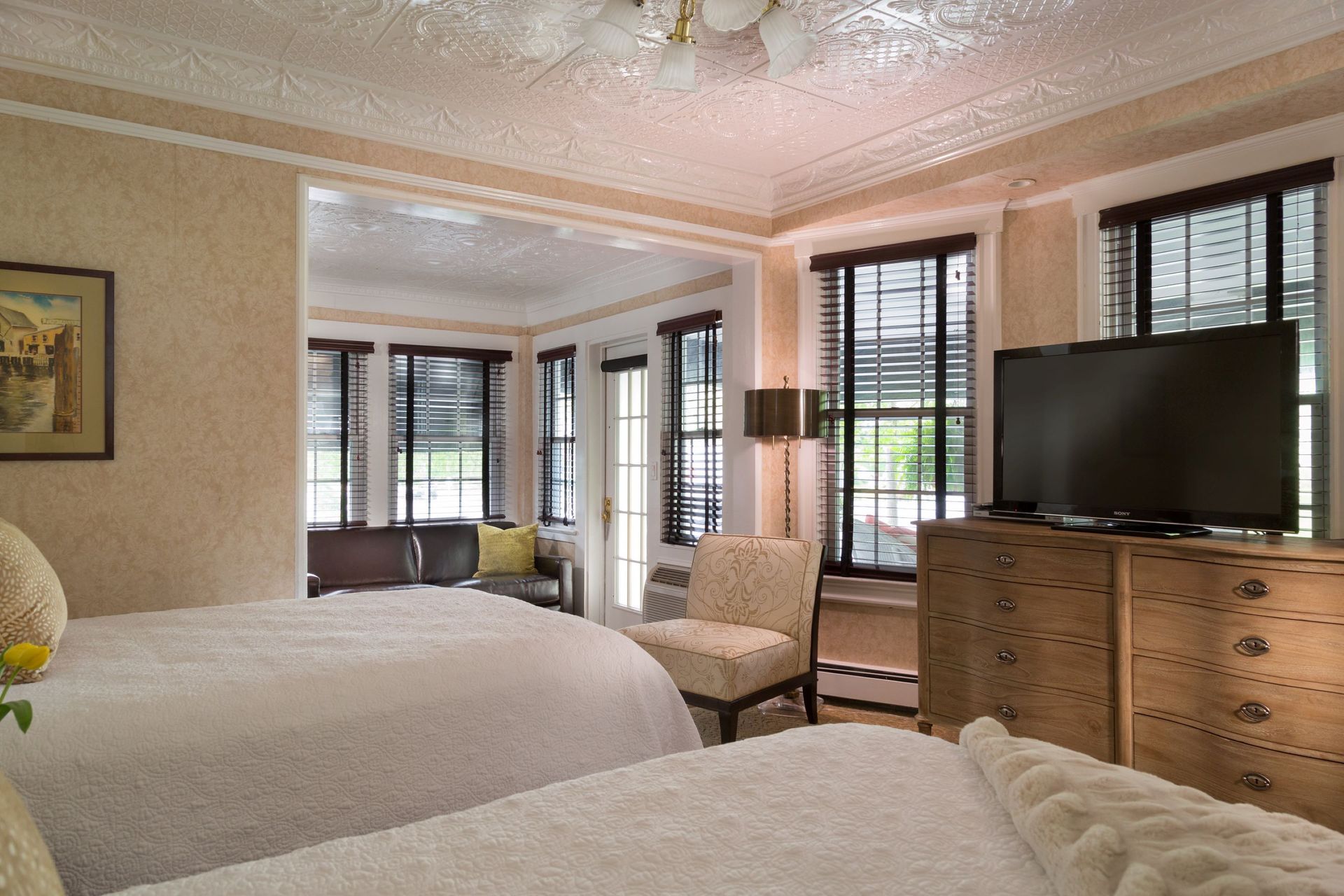 A hotel room with two beds , a dresser and a flat screen tv.