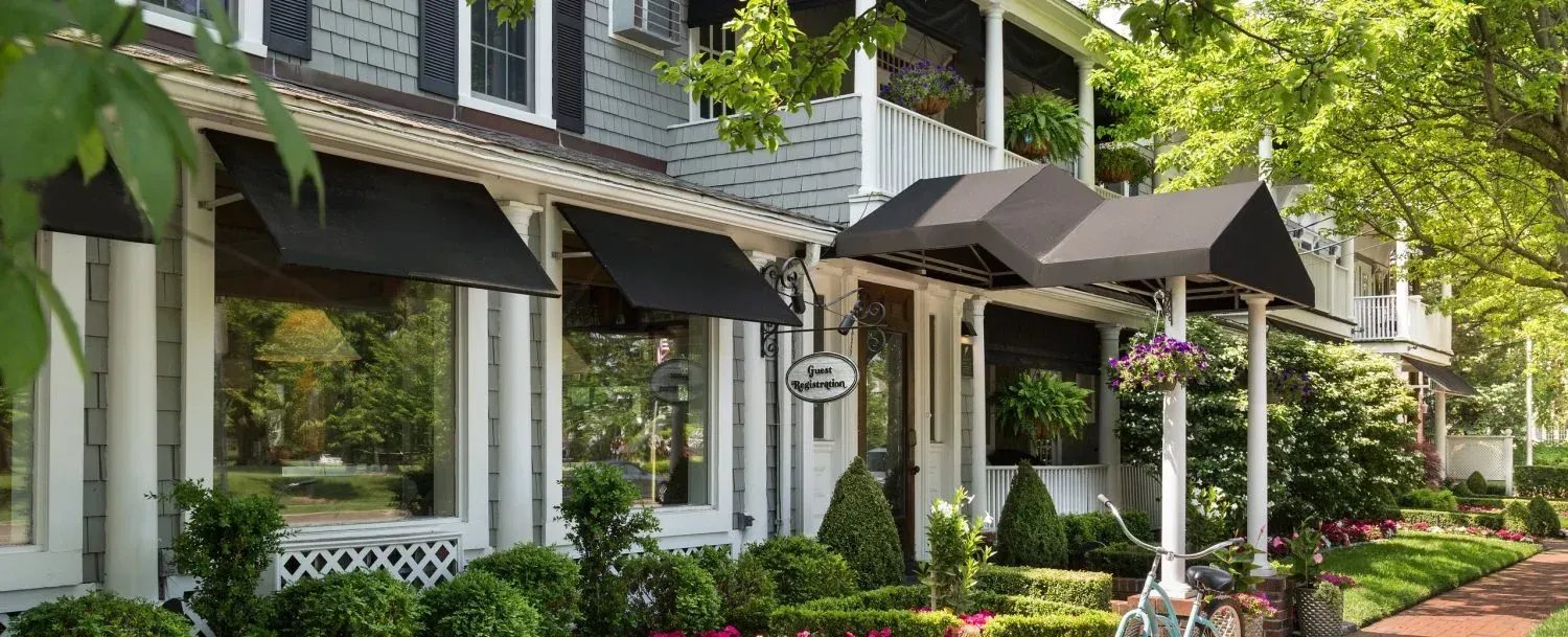 A white house with black awnings on the front of it.