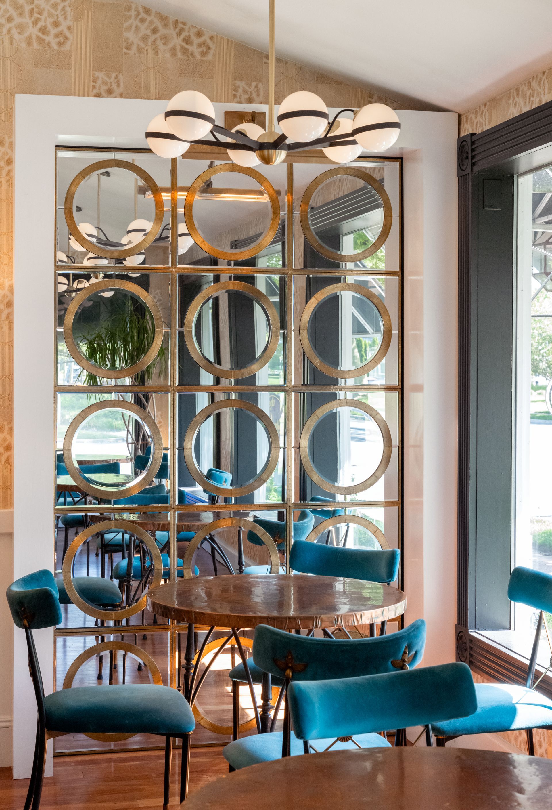 A dining room with tables and chairs and a mirrored wall.