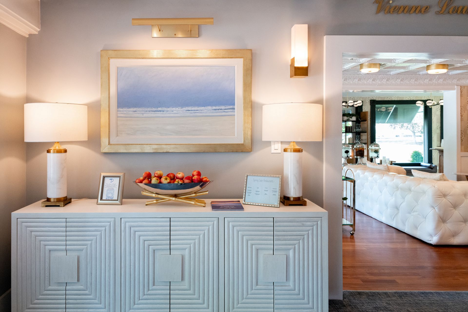 A white dresser with a picture on the wall above it