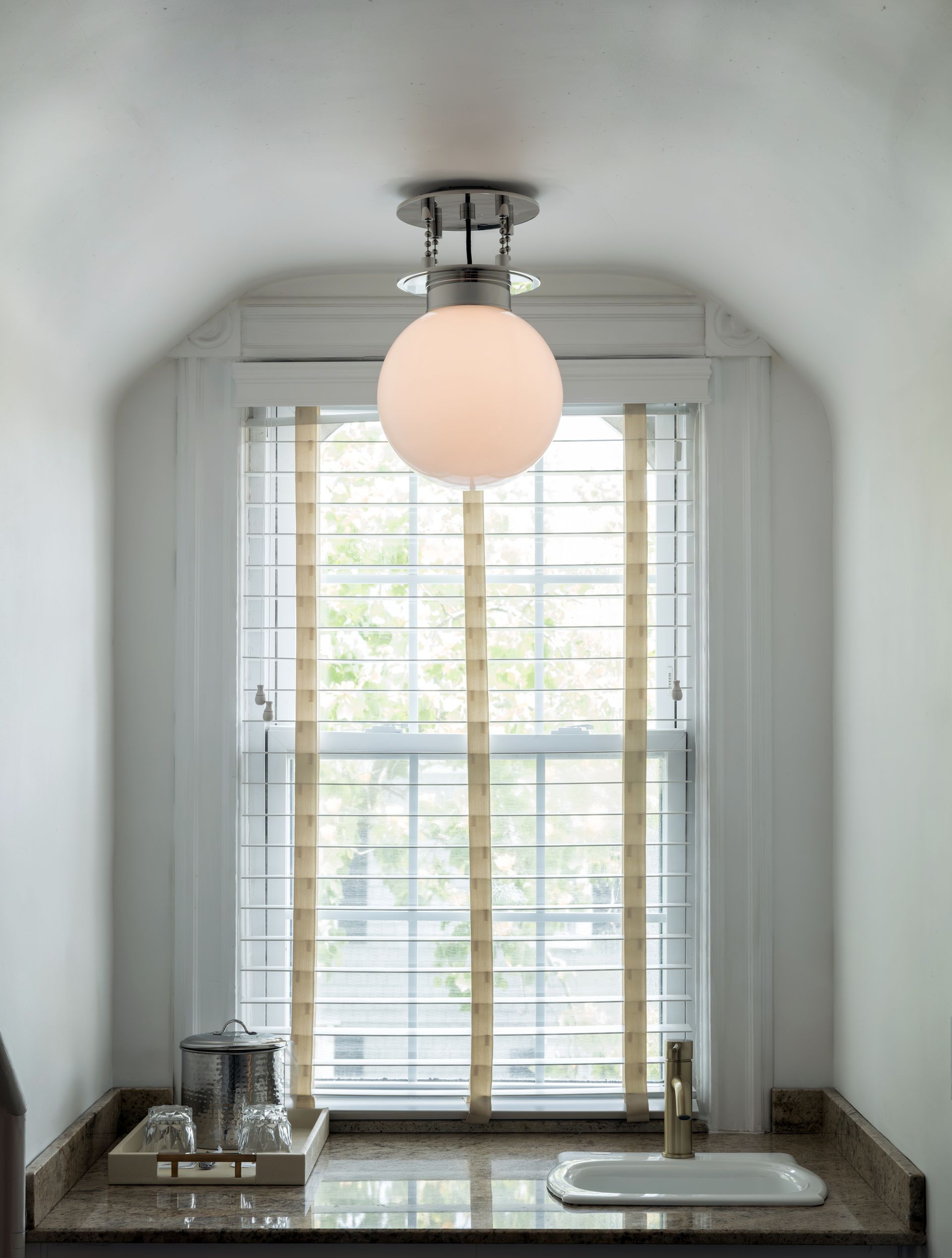 A bathroom with a sink and a window with blinds.