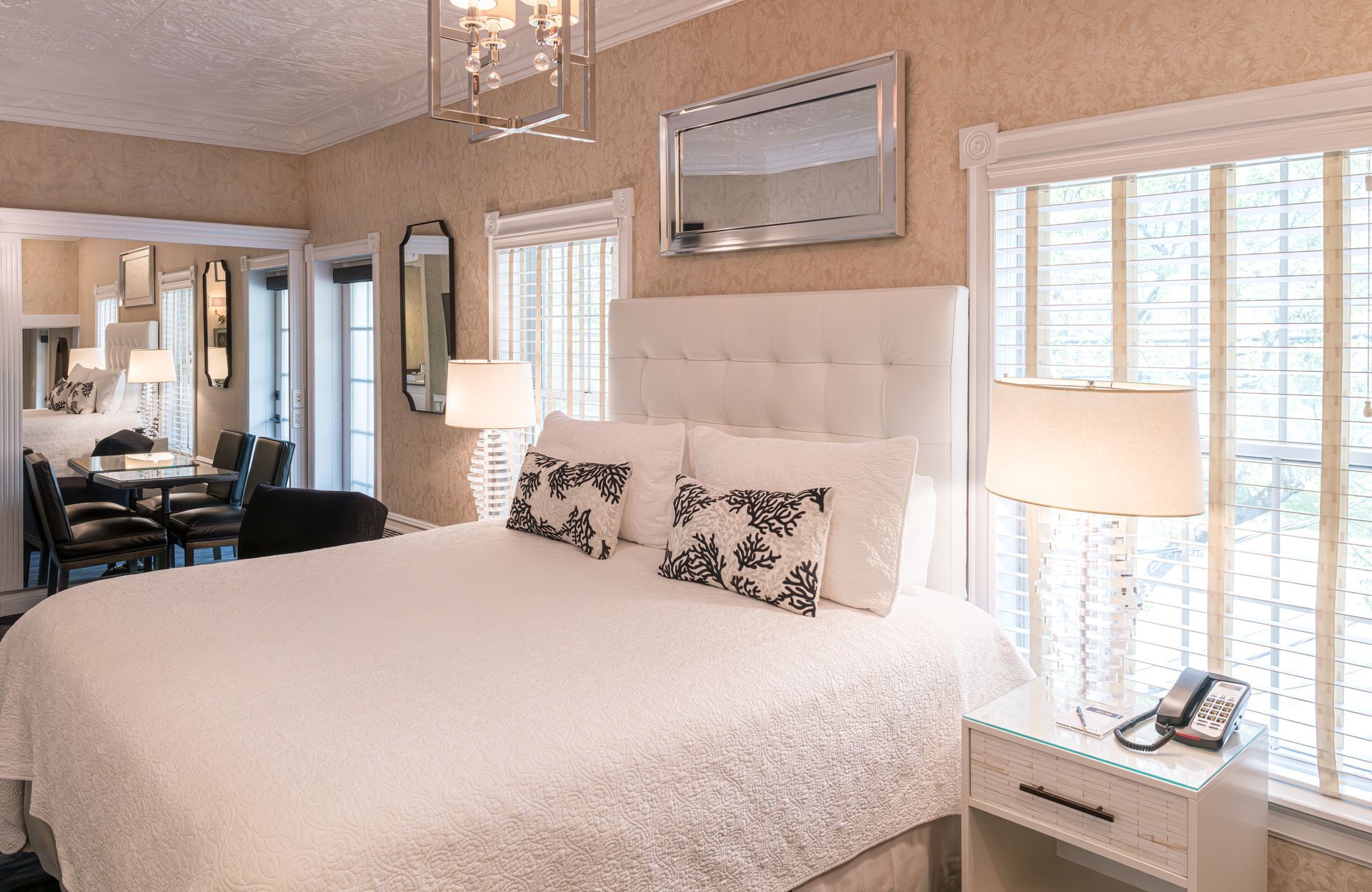 A hotel room with a king size bed , nightstand , lamps and a mirror.