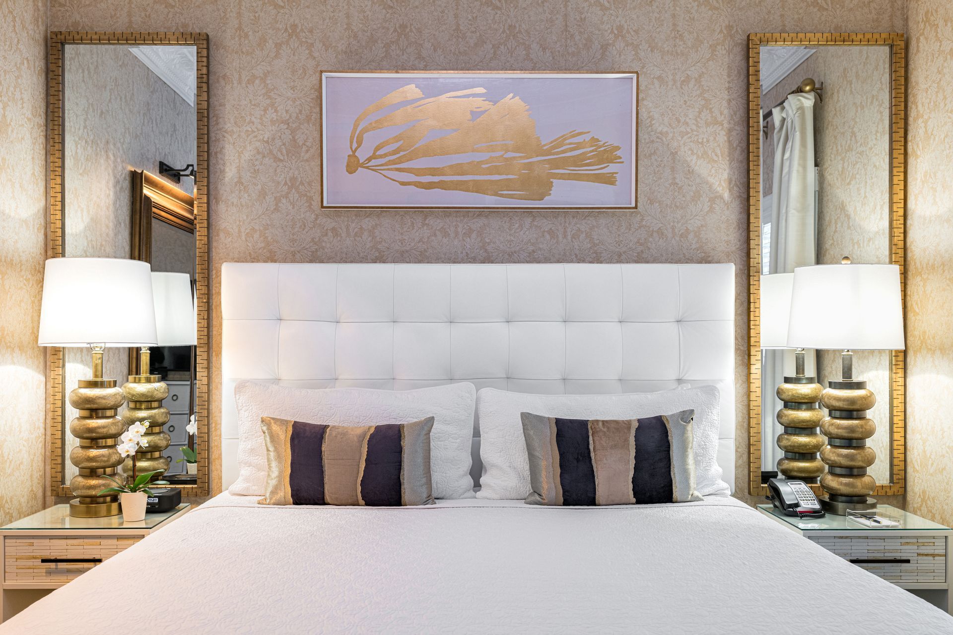 A hotel room with a bed , two mirrors , lamps and a painting on the wall.