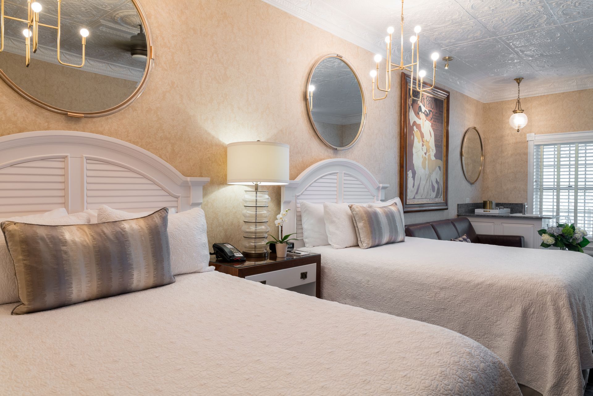 A hotel room with two beds and two mirrors on the wall.