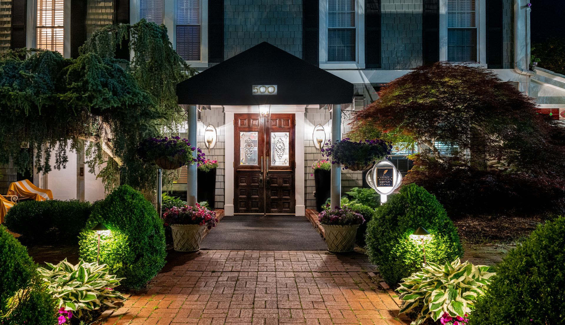 A large house with a brick walkway leading to the front door at night.