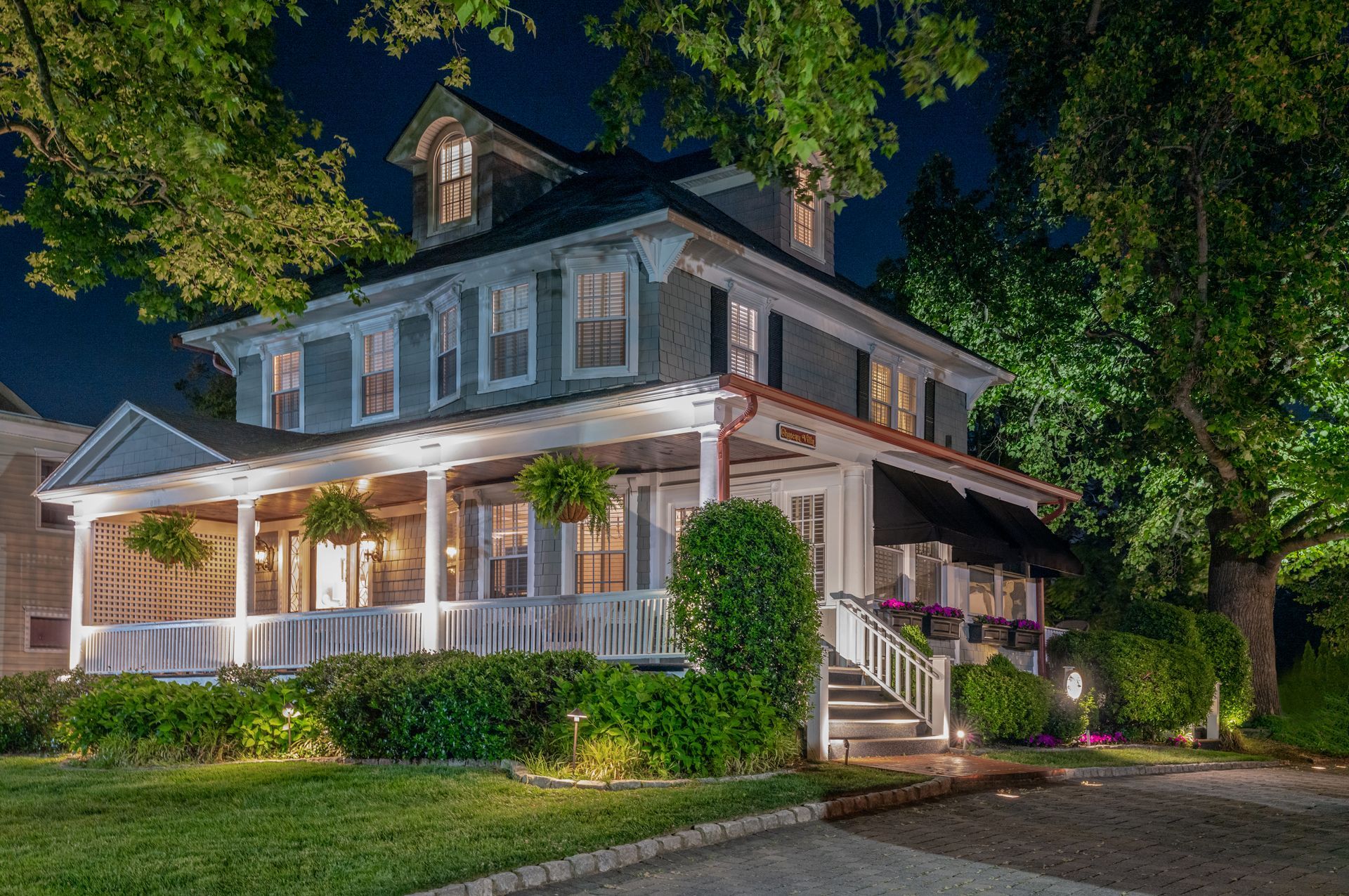 A large house with a large porch is lit up at night.