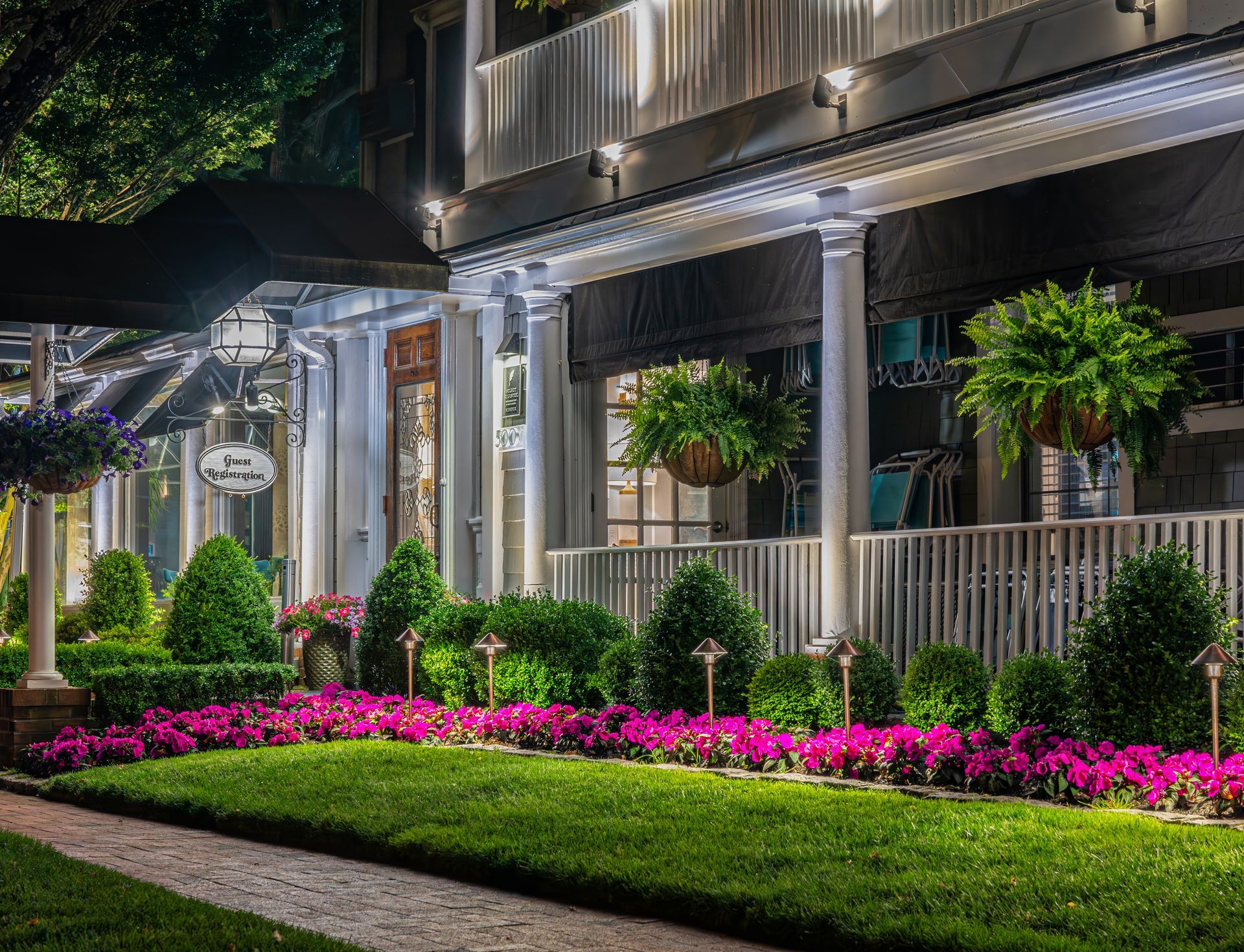 A large building with a porch and flowers in front of it