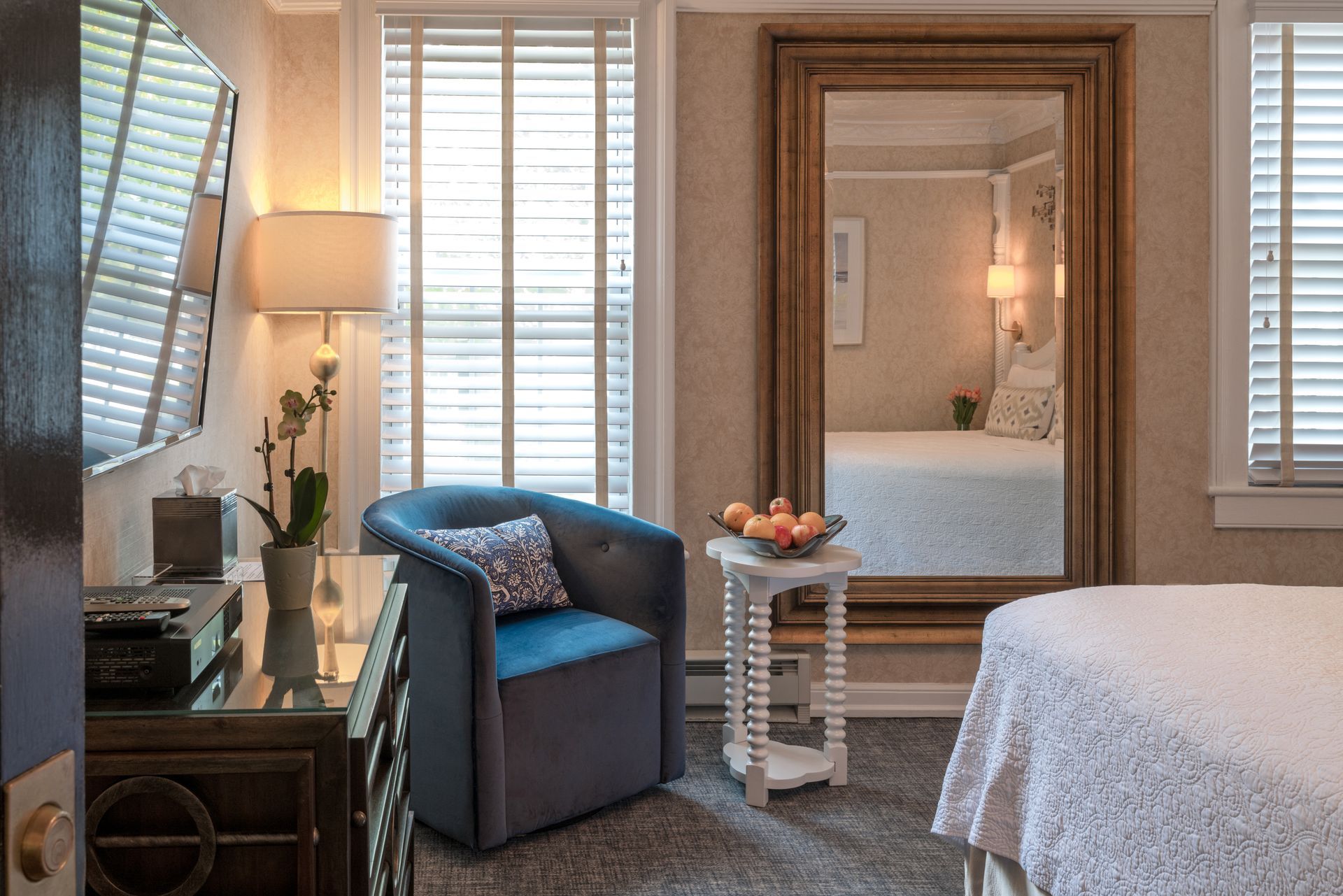 A hotel room with a large mirror and a chair.