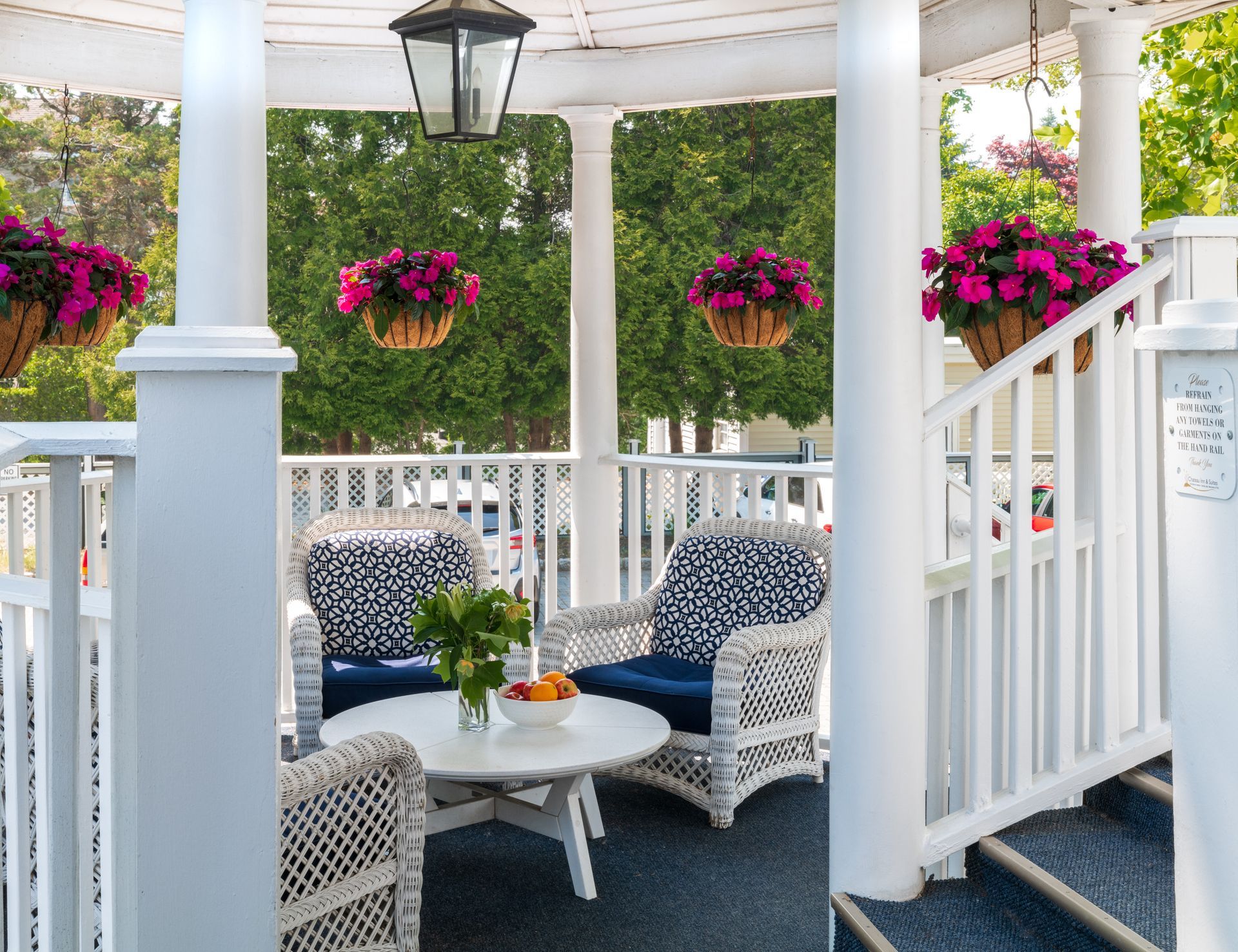A porch with wicker furniture and hanging baskets of flowers