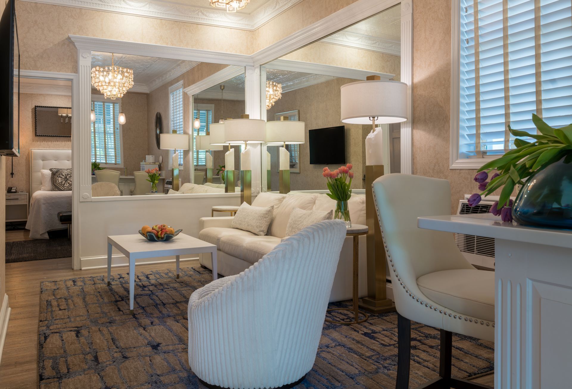 A living room with a couch , chairs , table and mirrors.