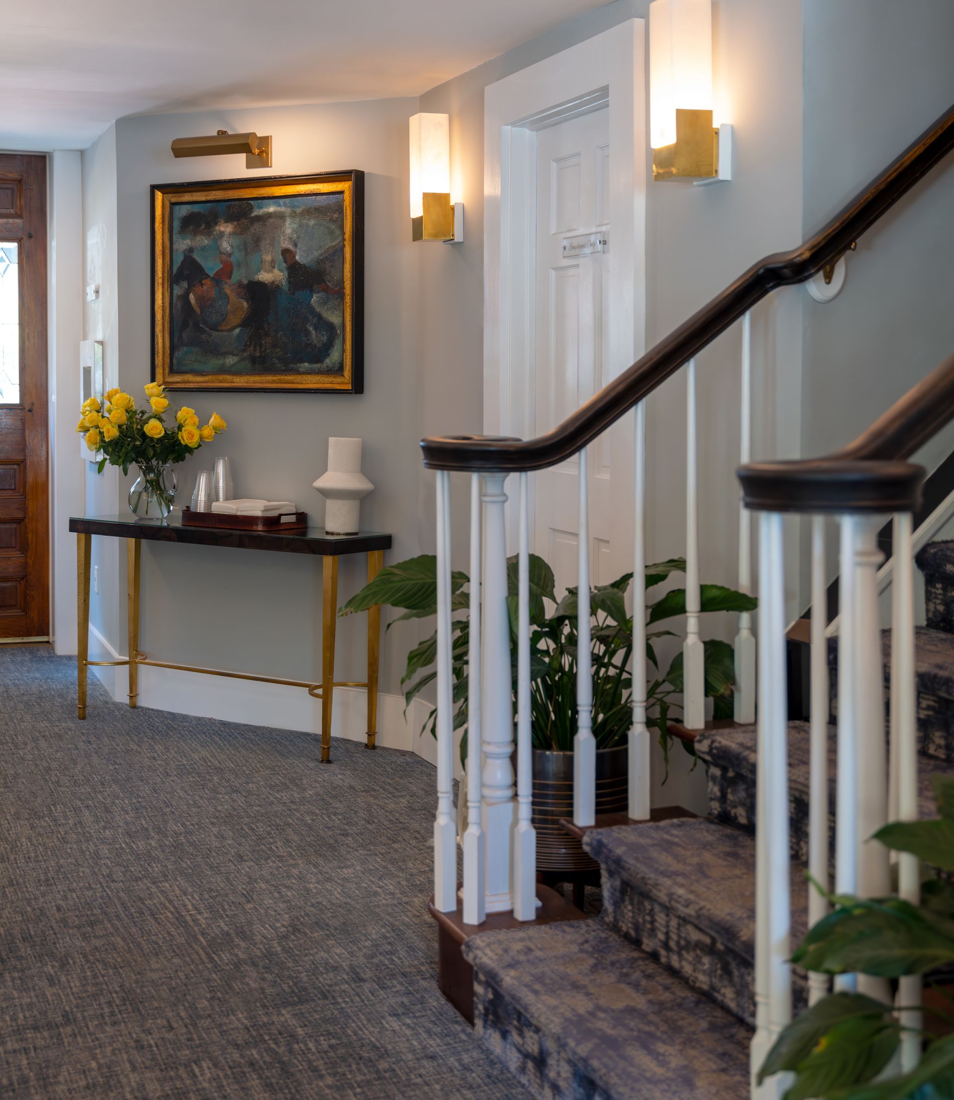 A hallway with stairs and a painting on the wall