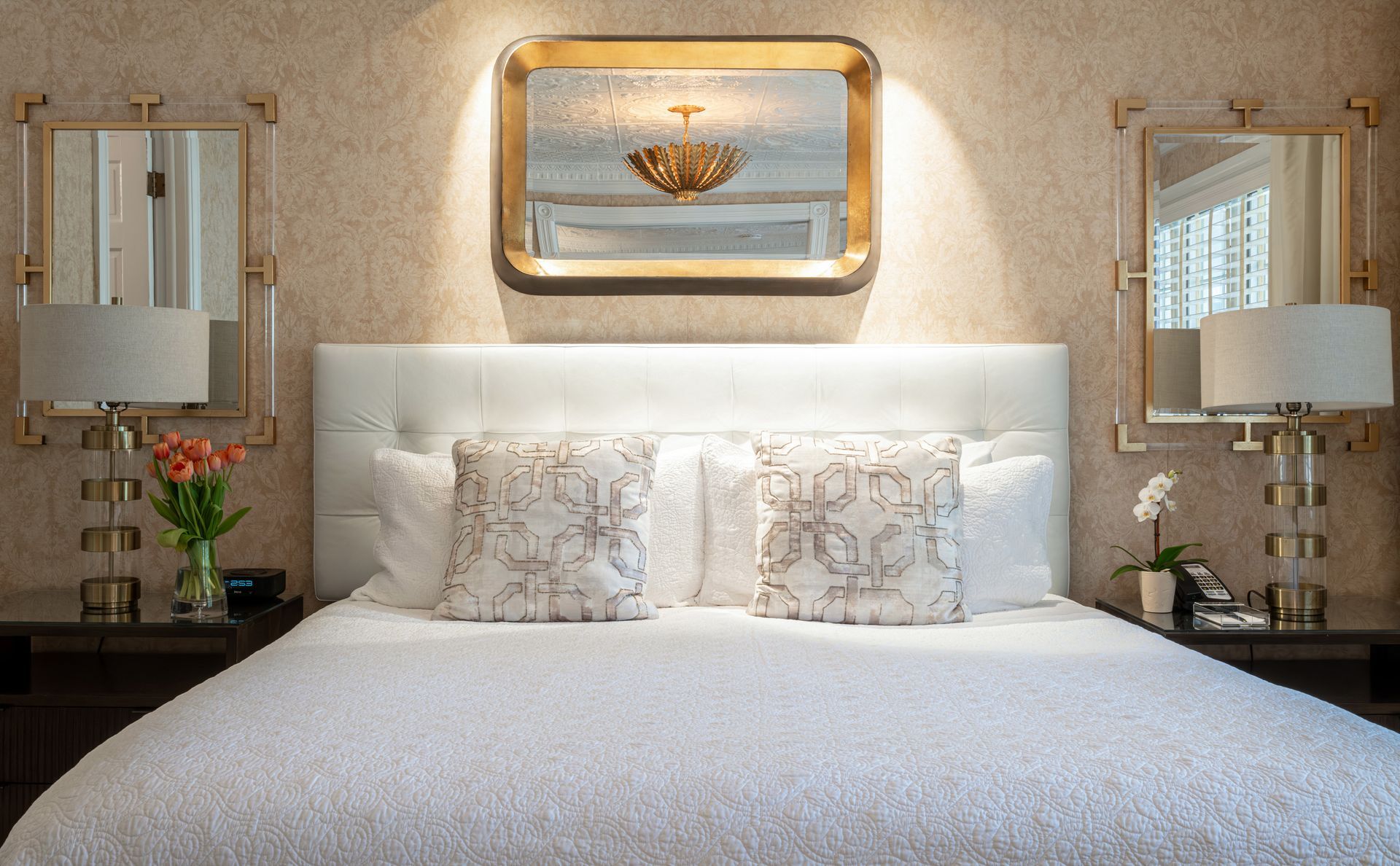 A bedroom with a bed and two mirrors on the wall