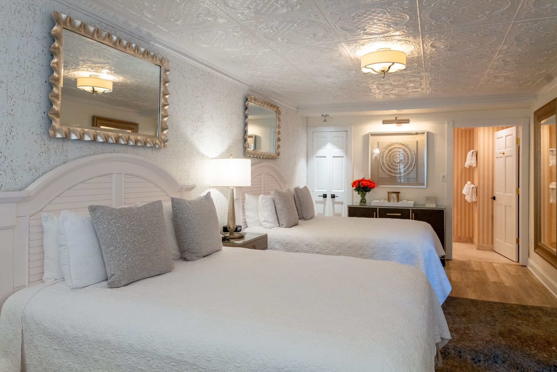 A hotel room with two beds and two mirrors on the wall.
