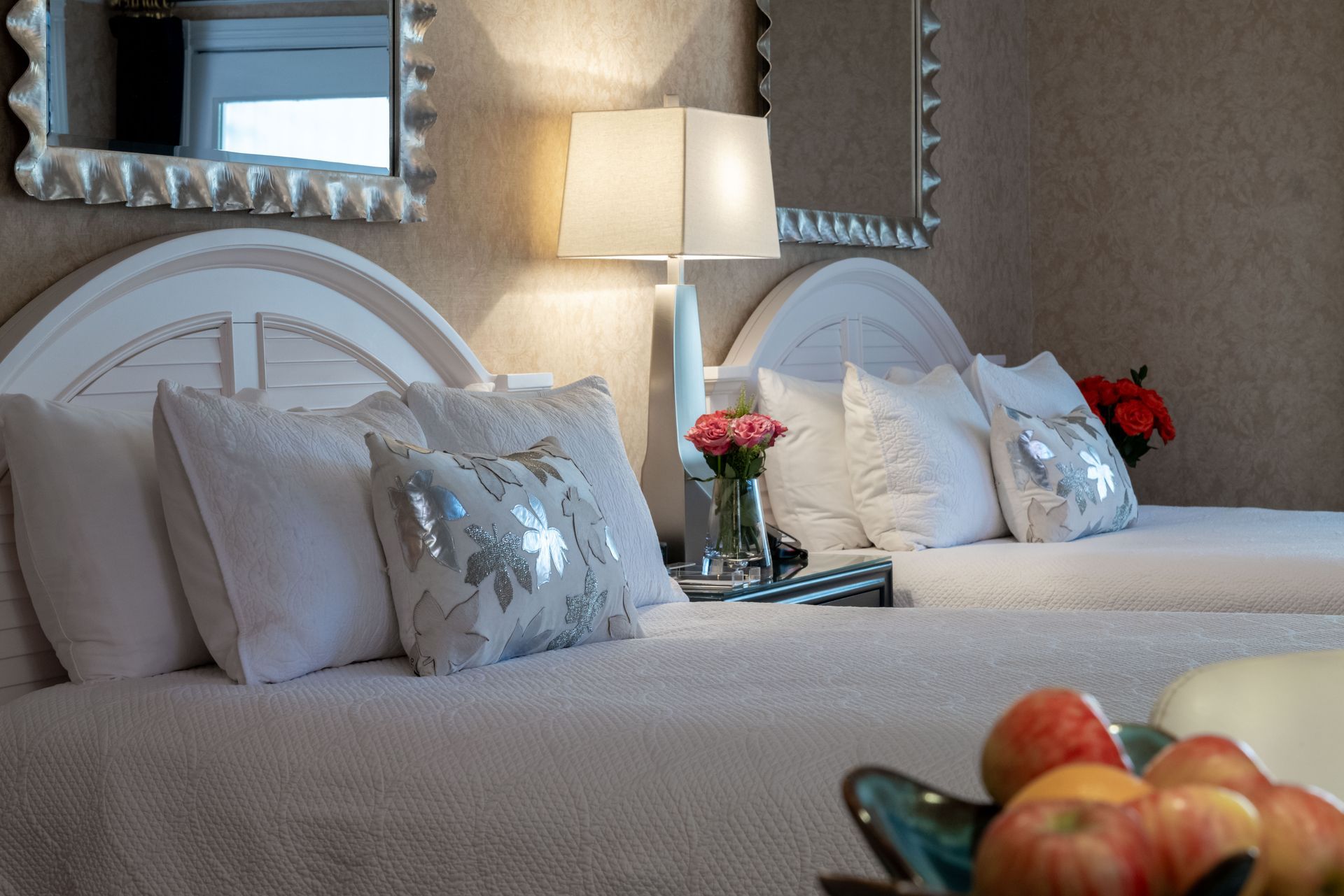 A hotel room with two beds and a bowl of apples