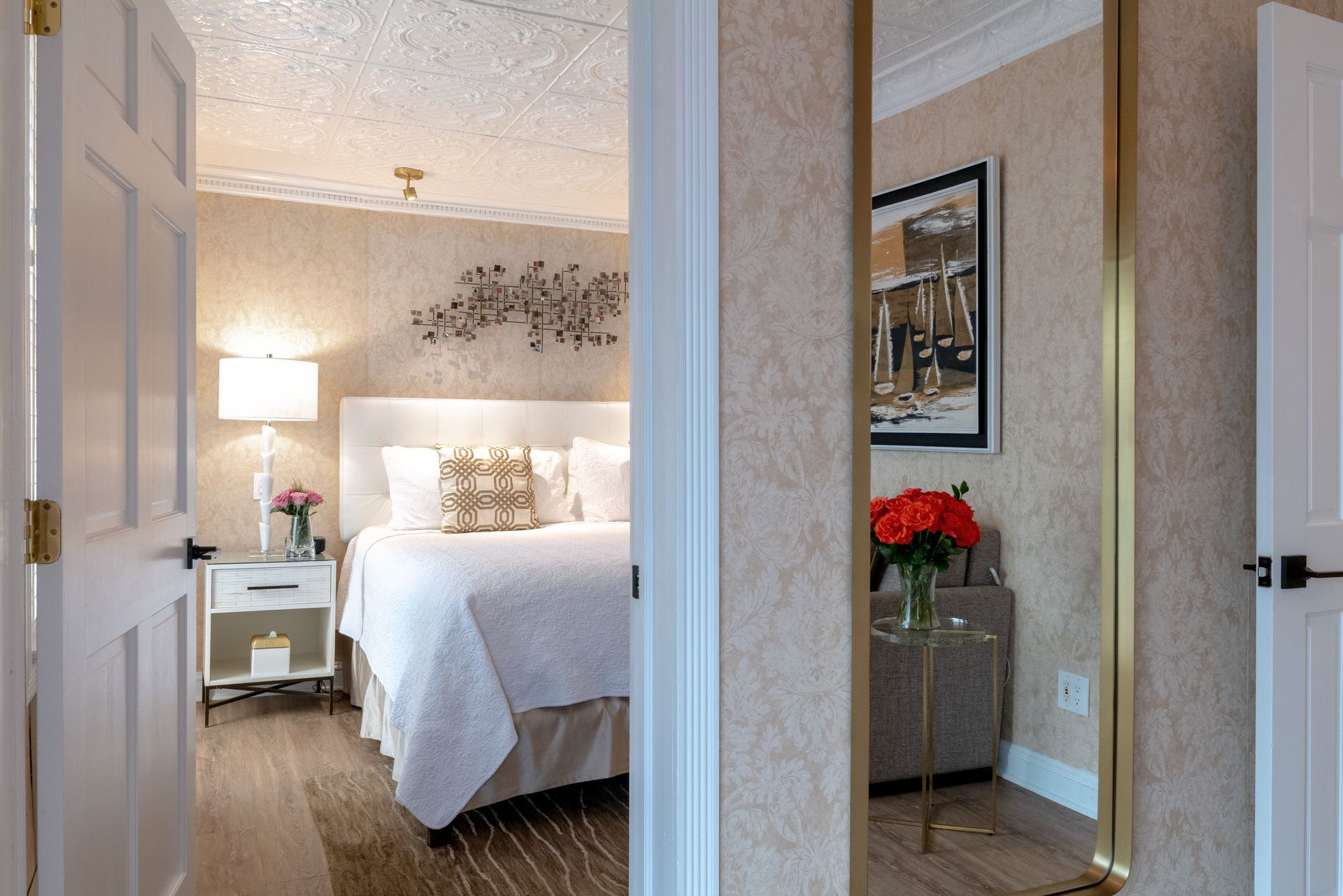 A bedroom with a bed , nightstand , table and mirror.