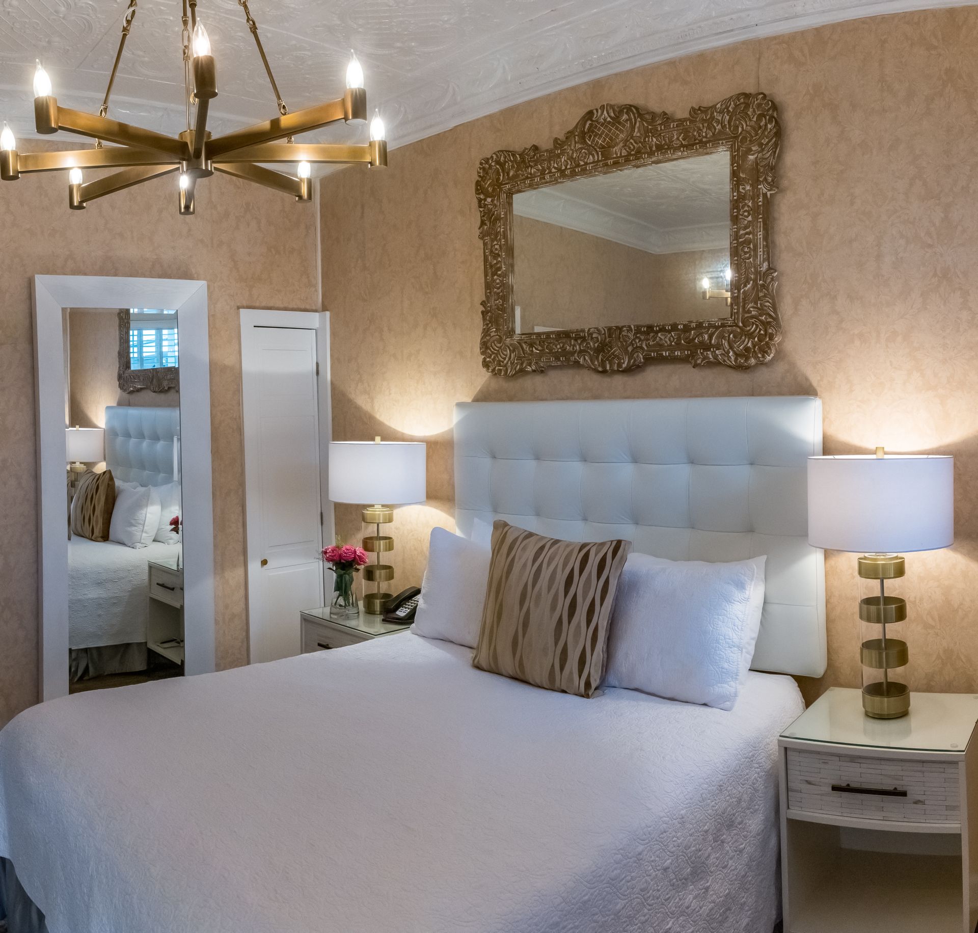 A bedroom with a bed lamps and a mirror