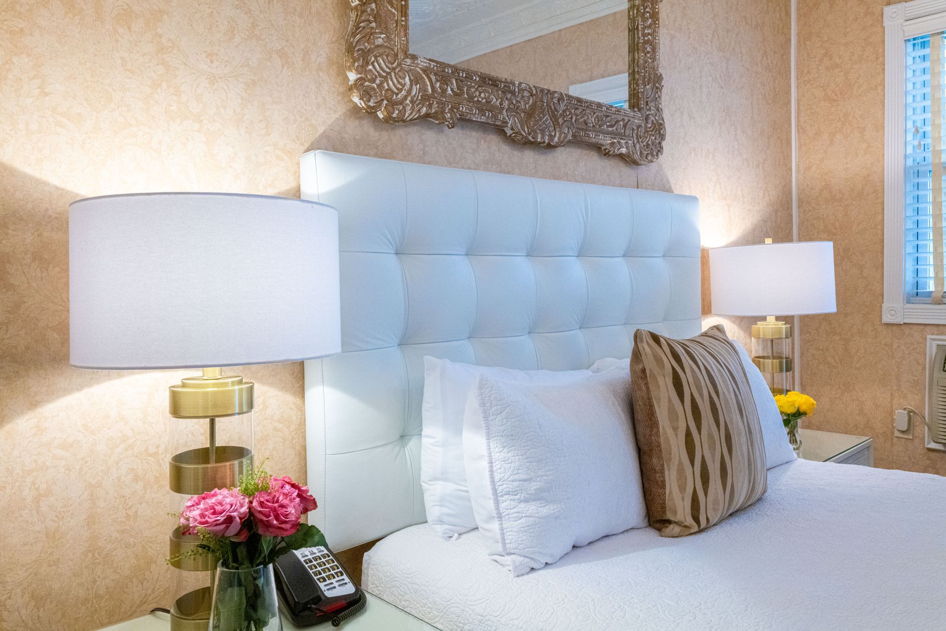 A hotel room with a bed , lamps , and a mirror.