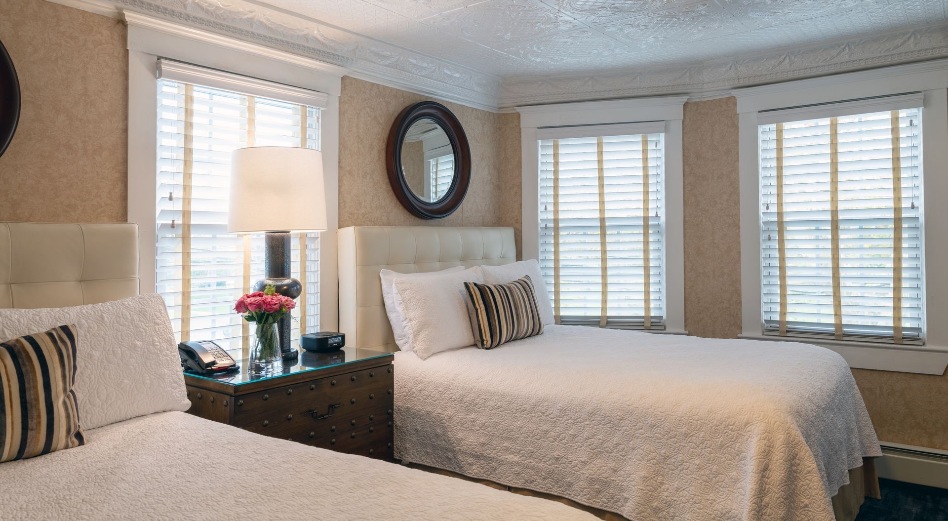 A hotel room with two beds , a nightstand and a mirror.